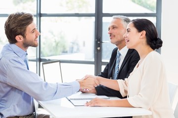 Businessman shaking hands with businesswoman in meeting