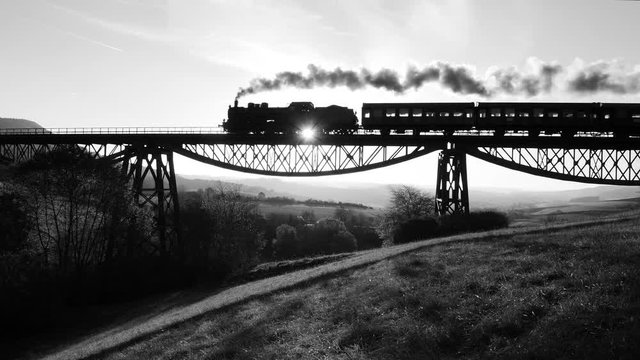 black and white background of steam engine locomotive crossing bridge road.