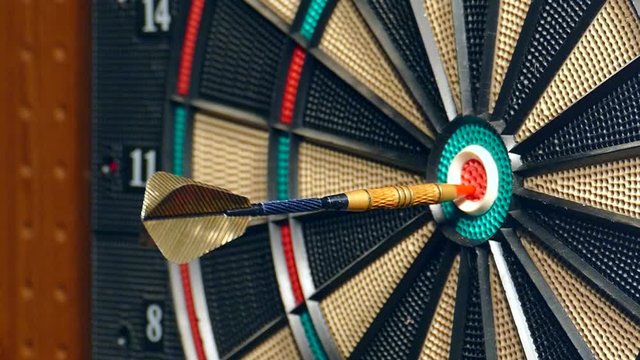 Three darts hit the double bullseye in slow motion.
