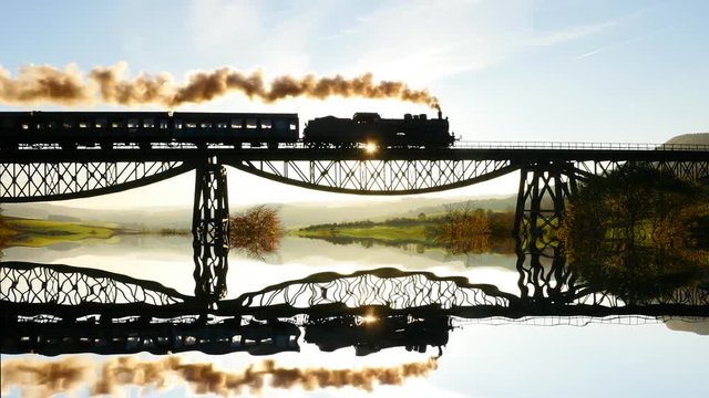 steam engine locomotive crossing bridge at sunset. mirror reflection silhouette background.