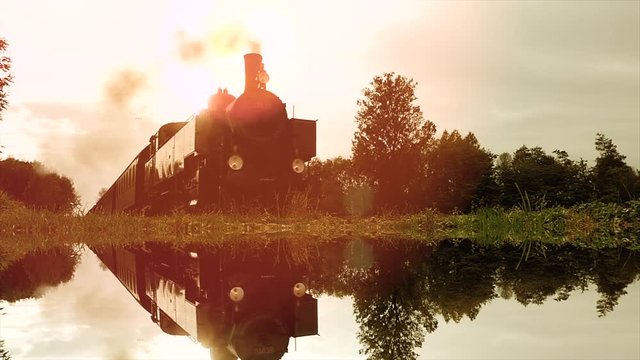 water mirror reflection of steam engine locomotive driving through countryside.