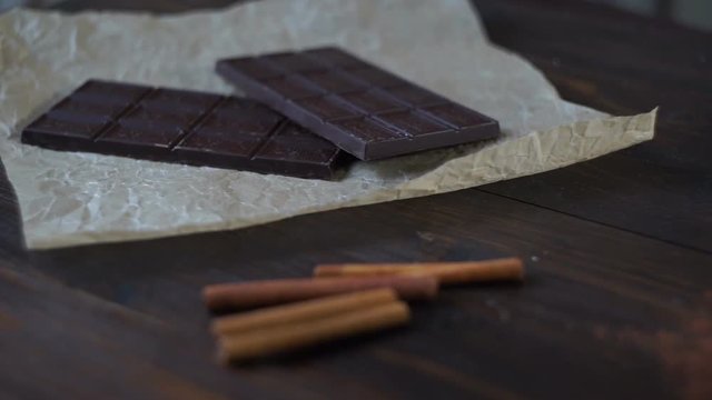 Sweet chocolate with cacao powder on wooden background. Dark chocolate bar. Black chocolate. Sweet ingredients. Sweet food. Panning on two bars of dark chocolate to cacao powder in glass