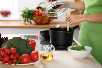 Young woman is cooking by the stove in the kitchen, close up.