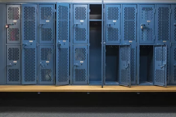 Rolgordijnen Blue metal cage lockers in a locker room with some doors open and some closed with a wooden bench © clsdesign