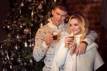 Merry Christmas. Young couple celebrating New Year at home. Man and woman drinking cocoa