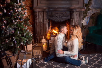 Merry Christmas. Young couple celebrating New Year at home. Man and a woman by the fireplace