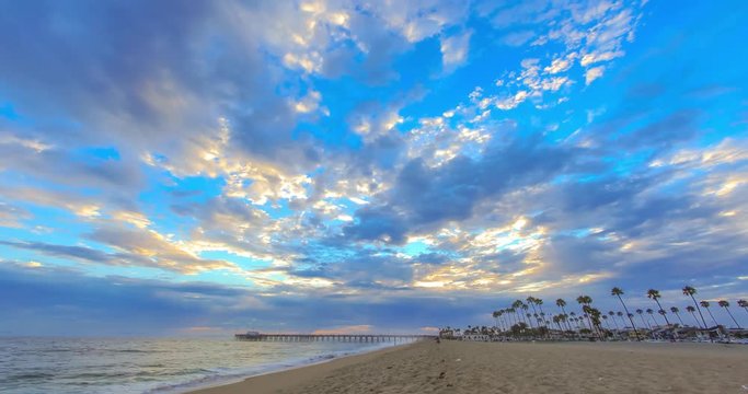 Sunset time lapse at the Newport Beach Pier at the beach with moving clouds and colors in the sky
