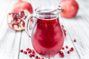 Portion of Pomegranate juice on wooden background (selective foc