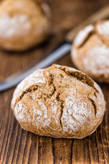 Naklejka premium Wholemeal Roll (selective focus) on vintage wooden background