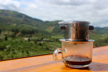 Drip coffee on table in foreground with green jungle background