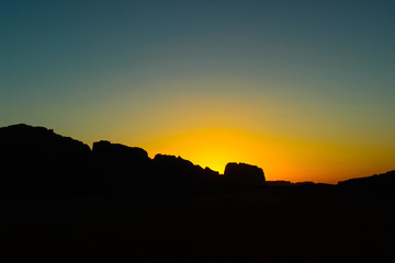 Sun behind dark silhouetted mountains