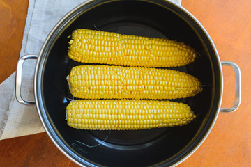 golden corn in black bowl on brown table top view