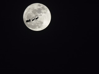 Obraz premium Santa Claus silhouette on full moon in the darkness sky