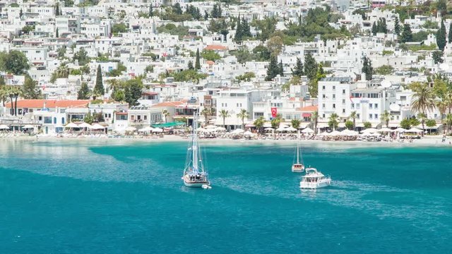 Waterfront Restaurants and Shops in Bodrum Turkey with White Resort Buildings bordering the Bay of Blue Aegean Sea Ocean Water on a Hot and Sunny Day