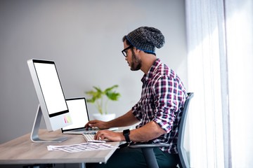 Serious hipster working at computer desk
