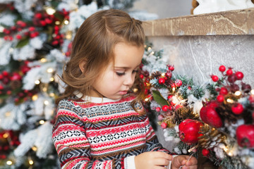 Portrait of pretty little girl looks at a Christmas toy at home