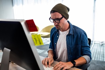 Portrait of serious hipster man working at computer desk