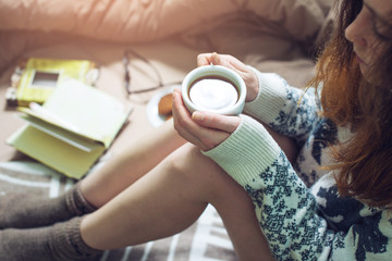 girl reading book in bed with warm socks drinking coffee