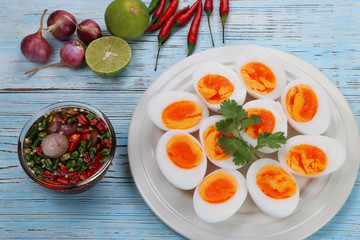 Boiled eggs and fish sauce with chili lemon and shallots on blue wood floor. Thai food