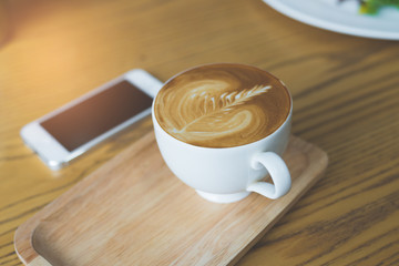 Mobile phone and coffee cup on office wooden table
