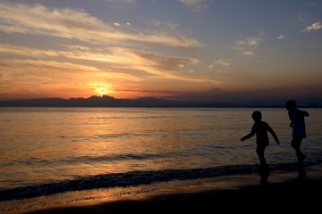 夕焼けの浜辺で遊ぶ子供たち