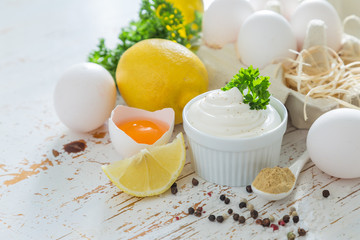 Mayonnaise sauce and ingredients on wood background