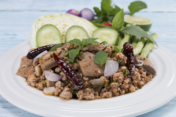 spicy minced pork salad on the wooden table in blue, thai food
