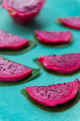 Colorful still life of red dragon fruit slices on green-blue background