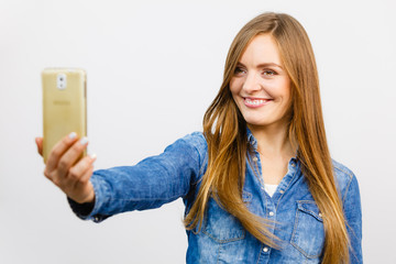 Fototapeta premium Woman in denim shirt taking self picture with phone