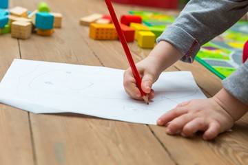 Little child drawing with pencil on white paper