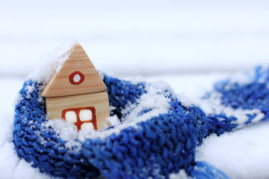 when behind a window snow and cold/ warming blue scarf around a wooden house in the winter season