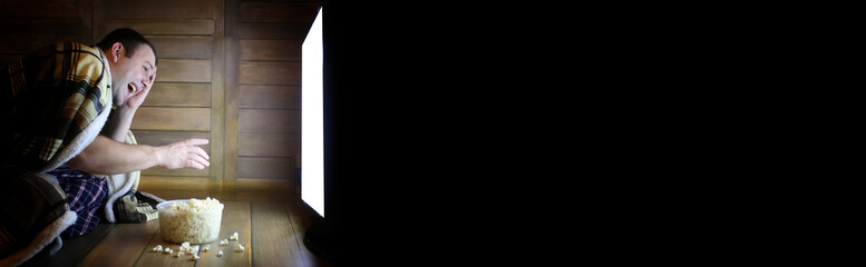 Naklejka premium man watching television at home on the floor