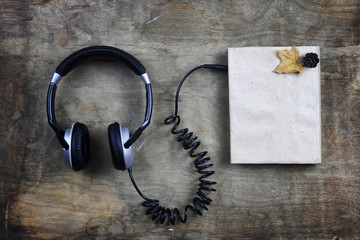 audiobook headphones and book on wooden table