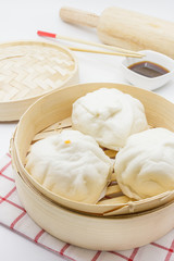 Steamed pork buns (chinese dim sum) in bamboo basket, serve with chopsticks and napkin on a white background, Closed up