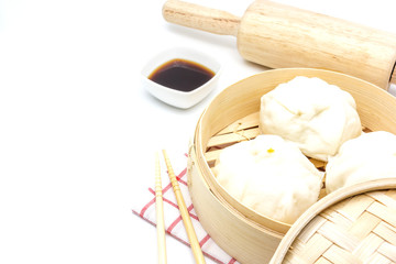Steamed pork buns (chinese dim sum) in bamboo basket, serve with chopsticks and napkin on a white background, Top view with copy space and text.