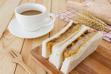 Katsu Sando (Japanese Pork Cutlet Sandwich), serve with napkin, cutlery Set and coffee cup on wooden table background, Closed up