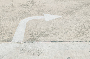 Closeup white painted arrow sign in right side on cement street floor textured background