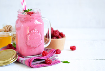 Berry smoothie in a glass jar on the breakfast with raspberries.