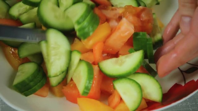 A fresh salad of red and orange tomato and green cucumber.