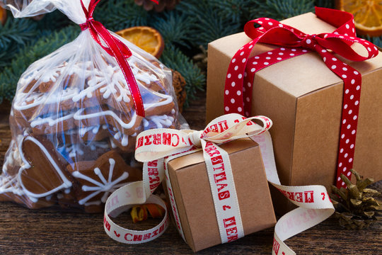 christmas gingerbread cookies in transparent bag with fir tree and gift boxes on wooden table close iup