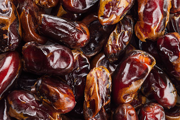Date fruit closeup background. Heap of dried shiny brown red date fruit. Top view.