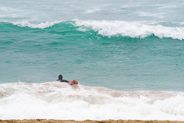 surfer on  board swims in an ocean.