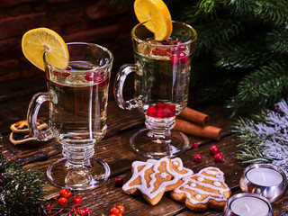 Christmas still life with pair mug decoration lemon slice hot drink on wooden table. Christmas cookies on plate with cinnamon sticks. White hot wine and berry under fir branches.