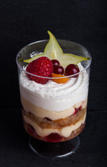 Small snacks trifle with fruits and cream in plastic glass on a