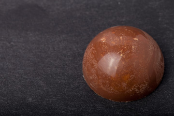 One chocolate candy on a slate background