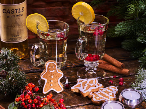 Christmas cookies on plate and bottle white wine. Christmas still life with pair mug decoration lemon slice hot drink on wooden table.