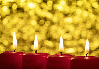Vier rote brennende Adventskerzen vor leuchtendem Hintergrund