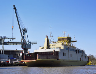 Fototapeta premium Freight shipping scene with industrial harbor cranes and industrial ship in the sunset.