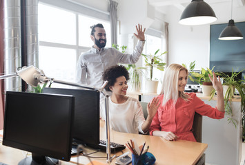 happy creative team waving hands in office