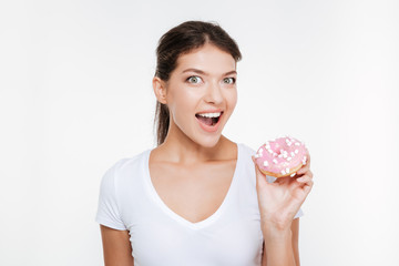 Funny young woman eating tasty donut on white background